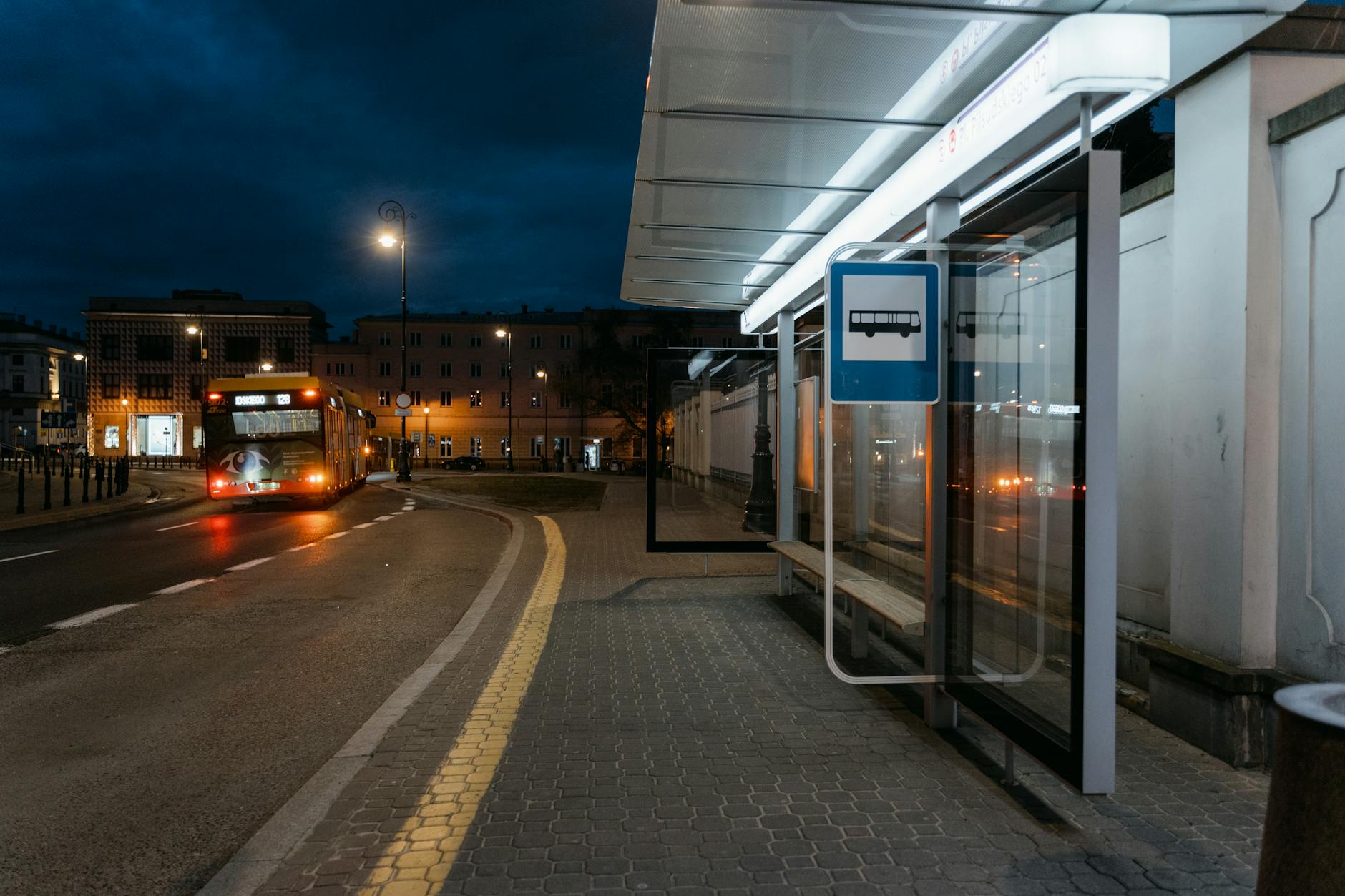 Nocny przystanek autobusowy z nadjeżdżającym miejskim autobusem