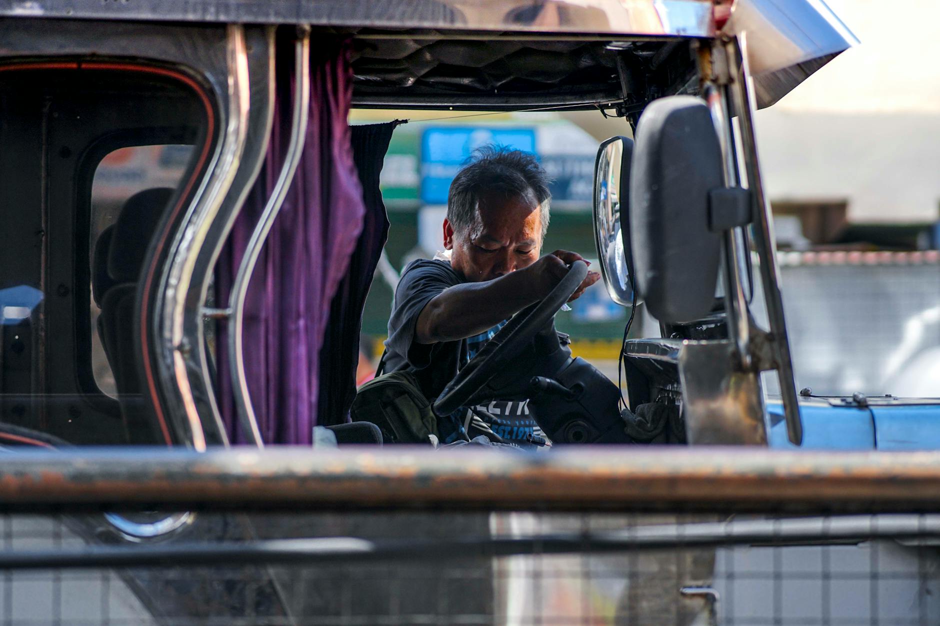Kierowca jeepneya drzemiący w pojeździe podczas dnia w ruchliwym mieście