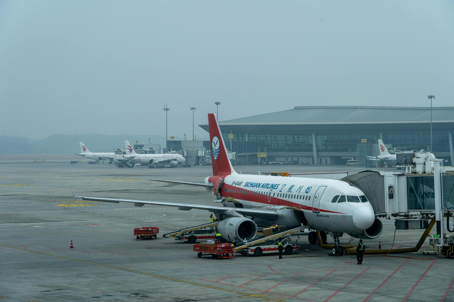 Samolot Sichuan Airlines Airbus A320 przy bramce na zatłoczonym lotnisku
