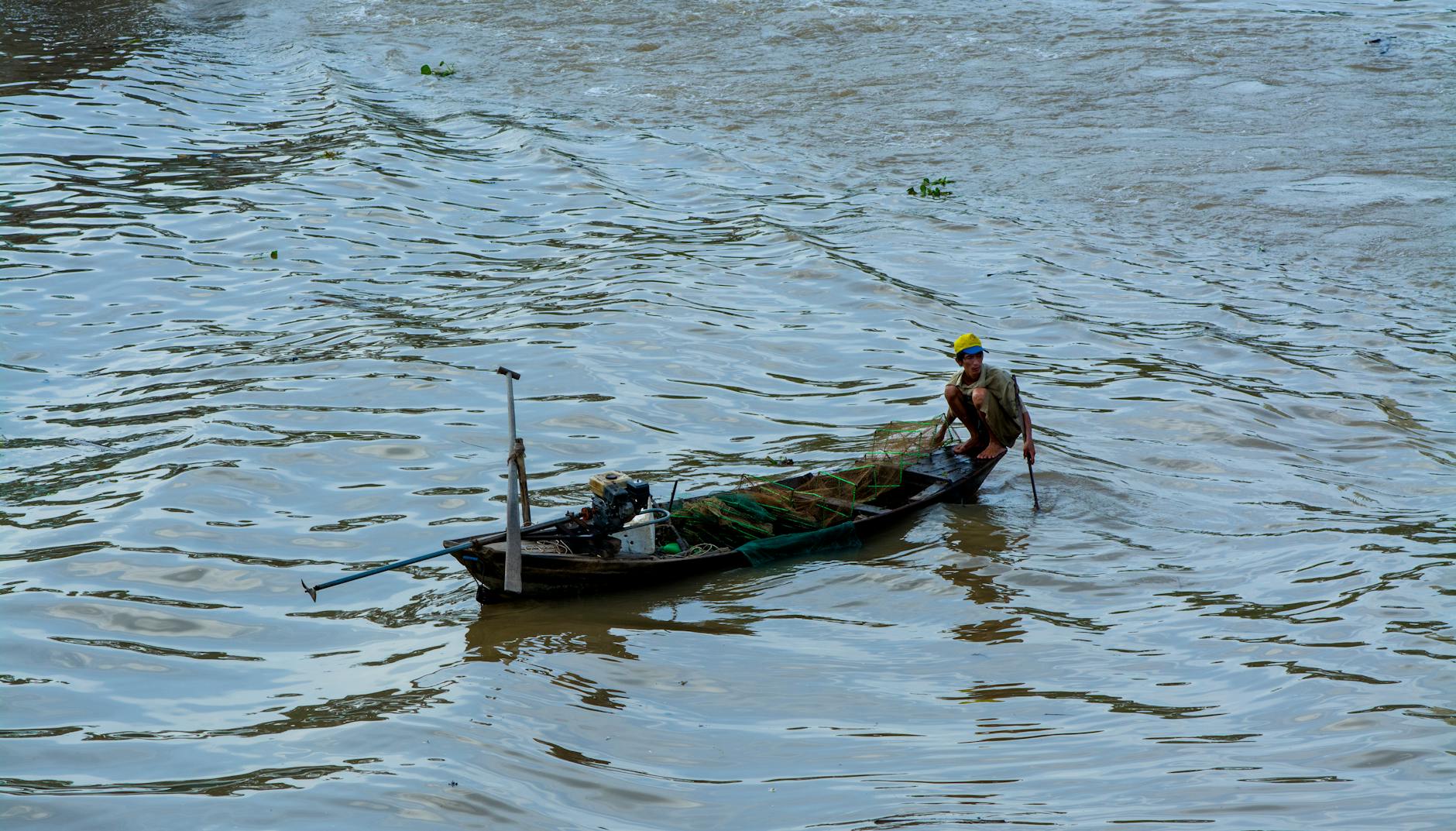 Wędkarz w małej łodzi na spokojnej rzece przy bezchmurnym niebie