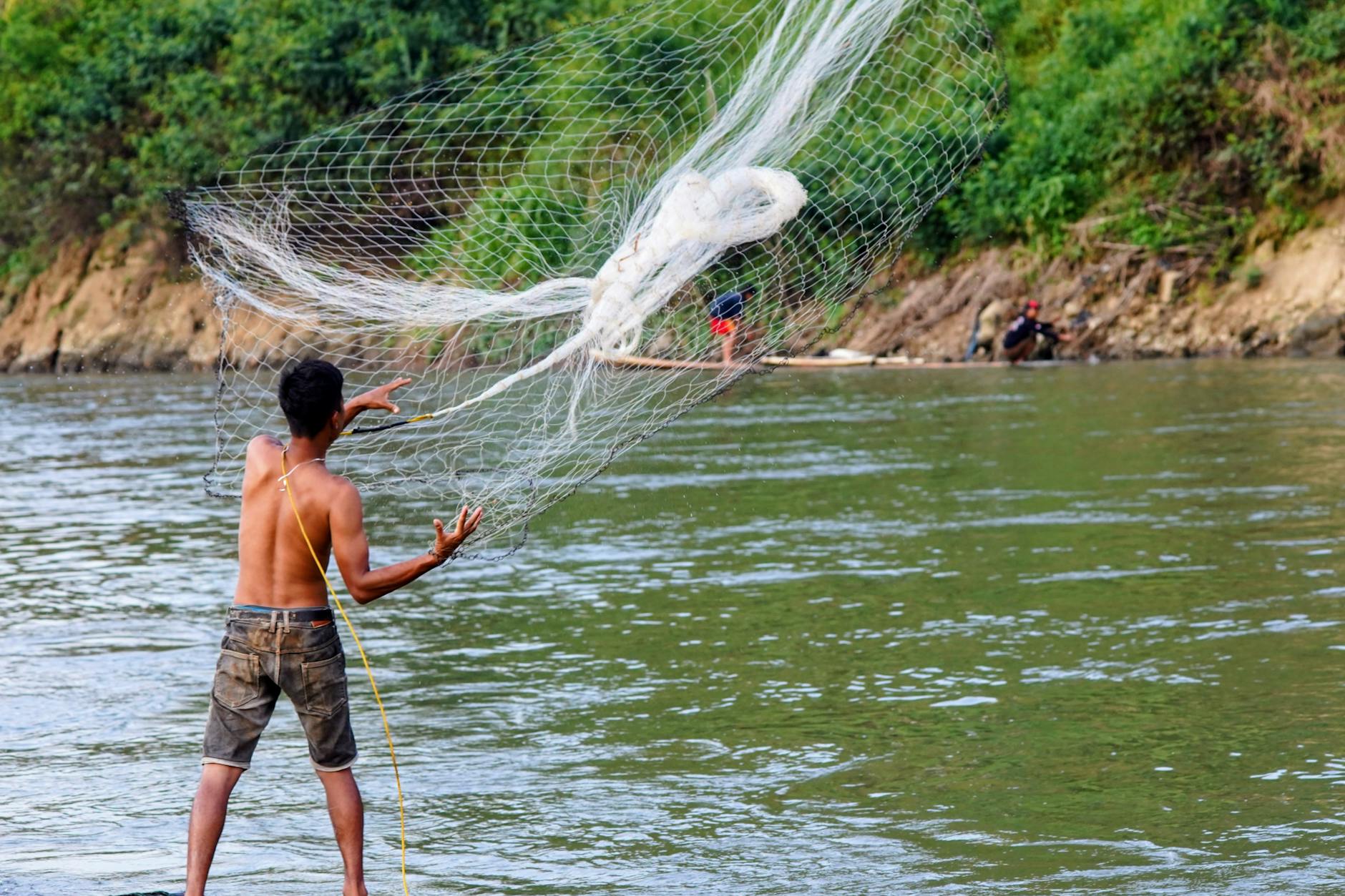 Wędkarz zarzuca sieć na spokojnej rzece w Indonezji