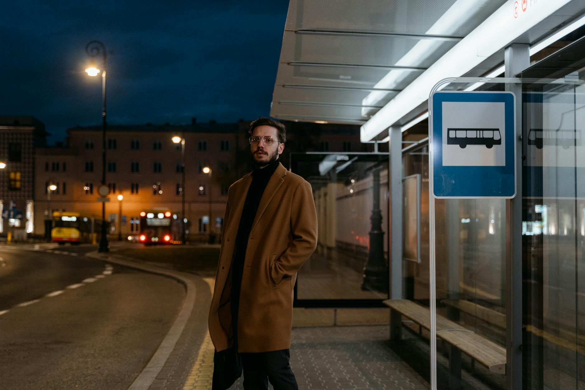 Powrót do Polski z Niemiec: jak znaleźć nocne kursy i sprawdzić realne godziny Mężczyzna w brązowym płaszczu czeka nocą na autobus na przystanku