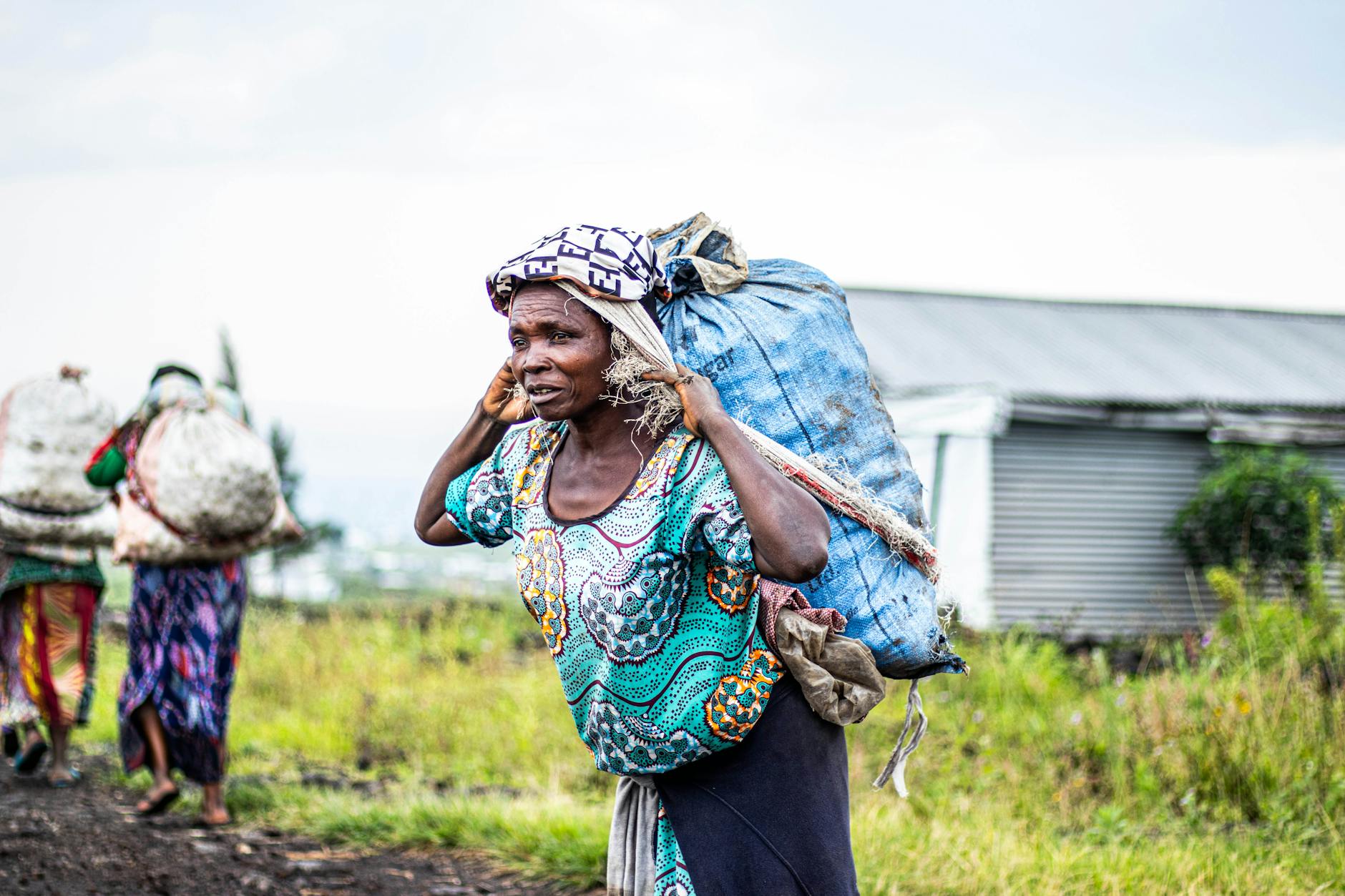 Afrykańskie kobiety na wsi niosą ciężkie pakunki na głowach