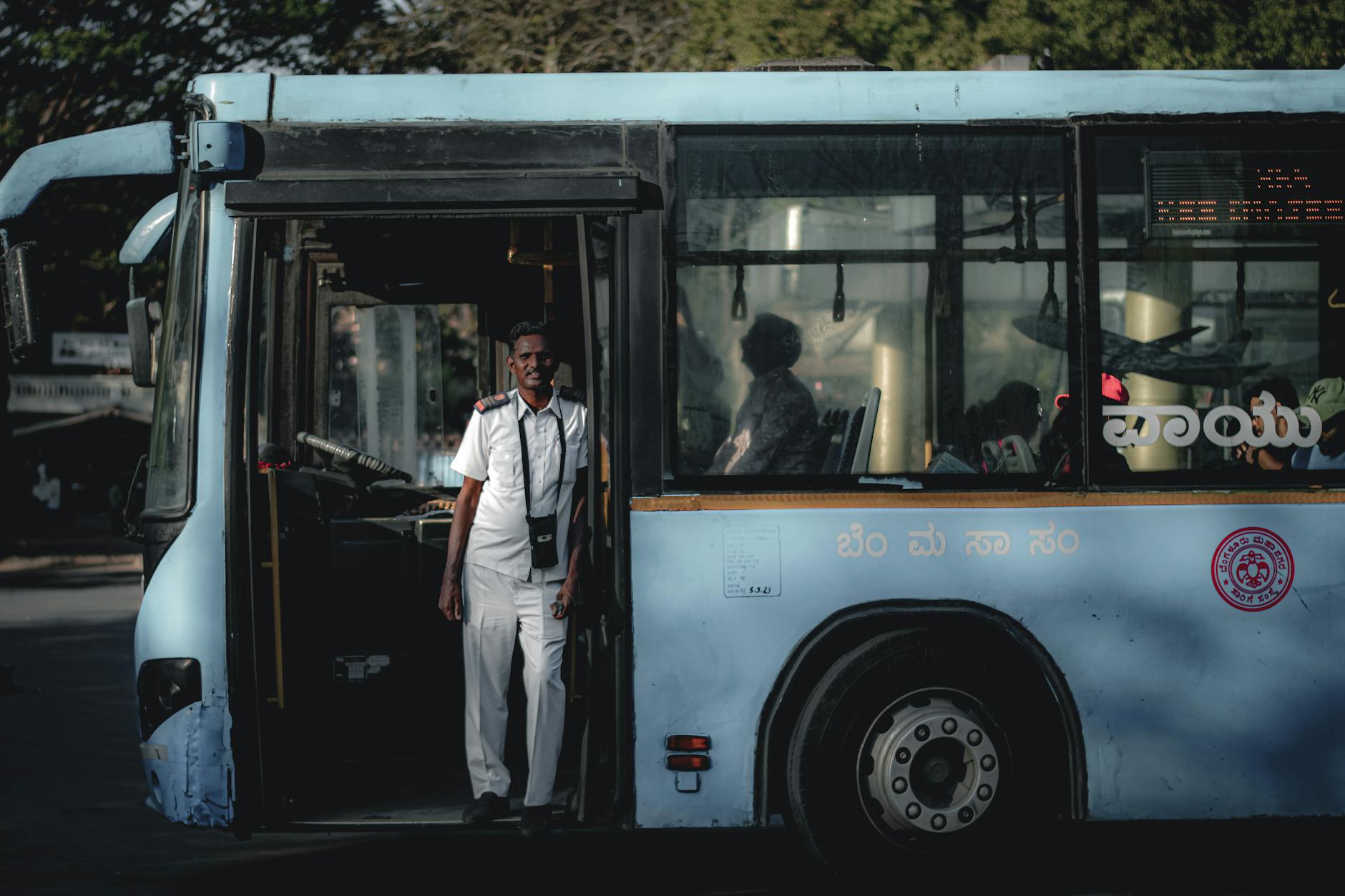 Kierowca autobusu w białym uniformie stojący w drzwiach pojazdu