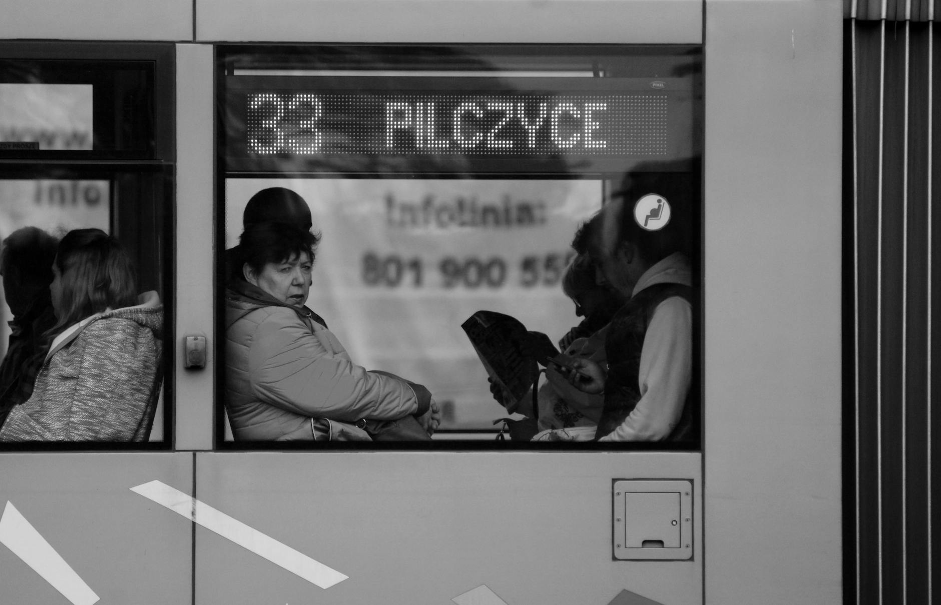 Pasażerowie jadący zatłoczonym autobusem miejskim w odcieniach szarości