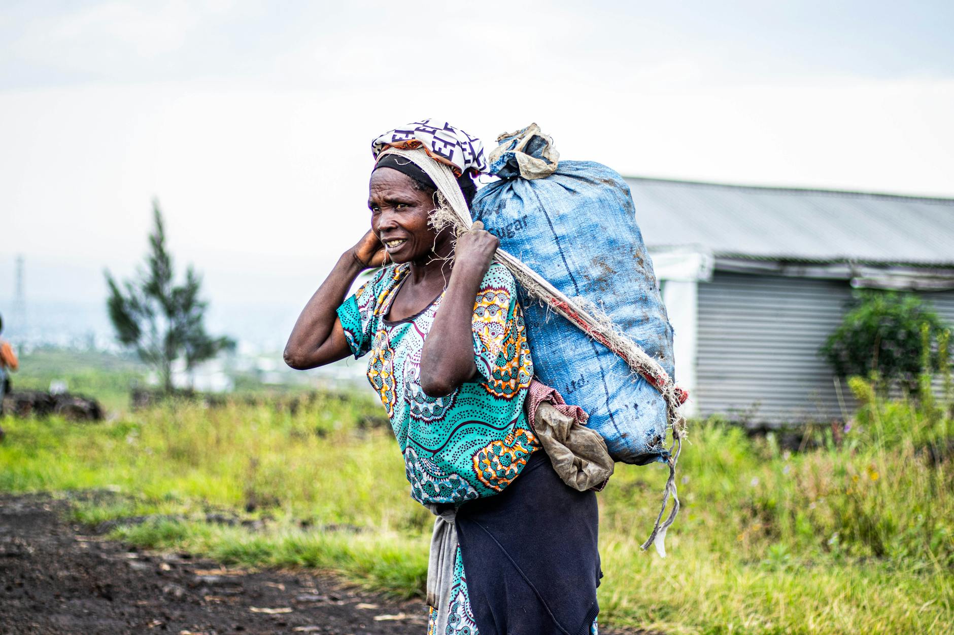 Starsza Afrykanka niesie duży worek na plecach na otwartej przestrzeni