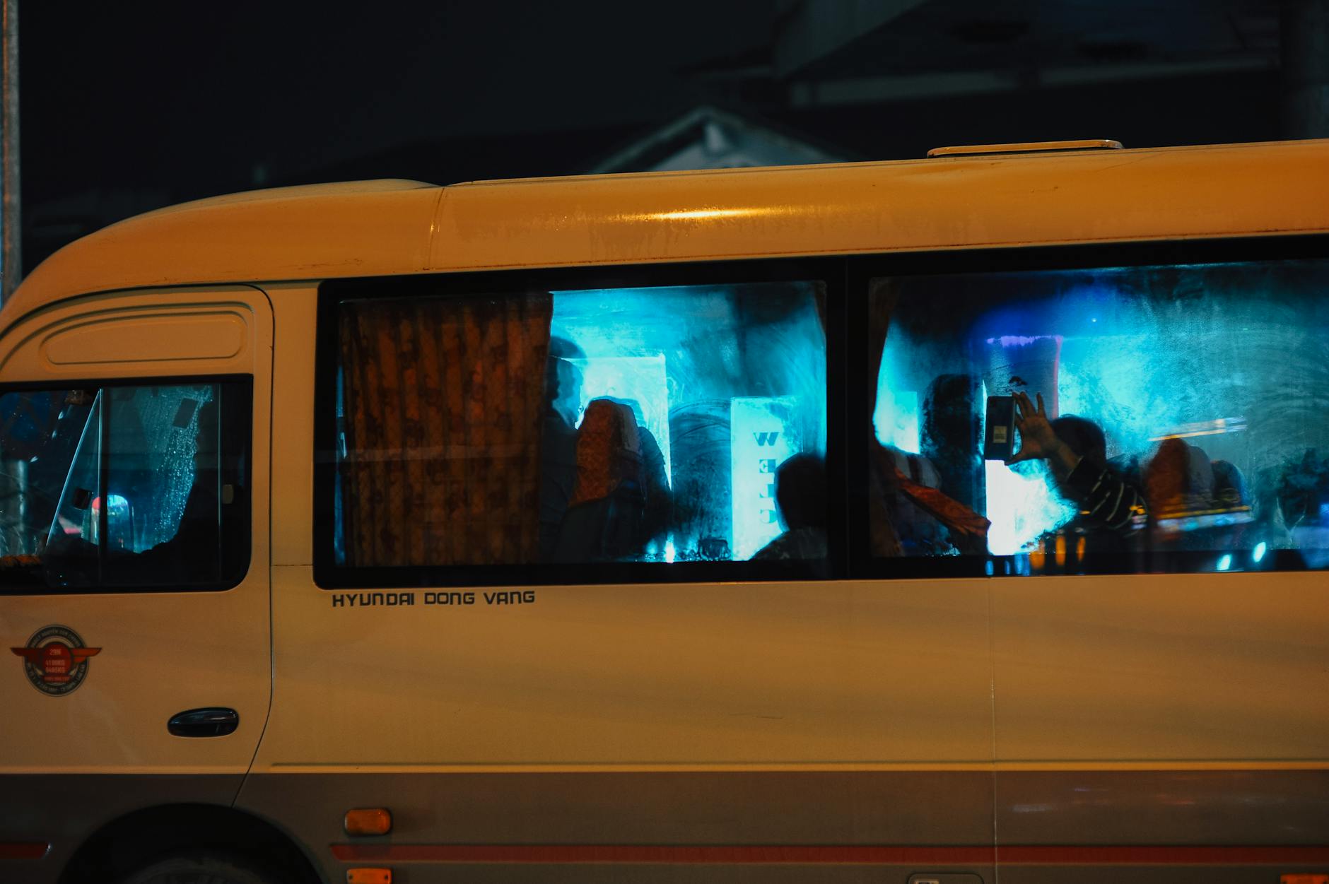 Pasażerowie nocnego autobusu na tle świateł miasta
