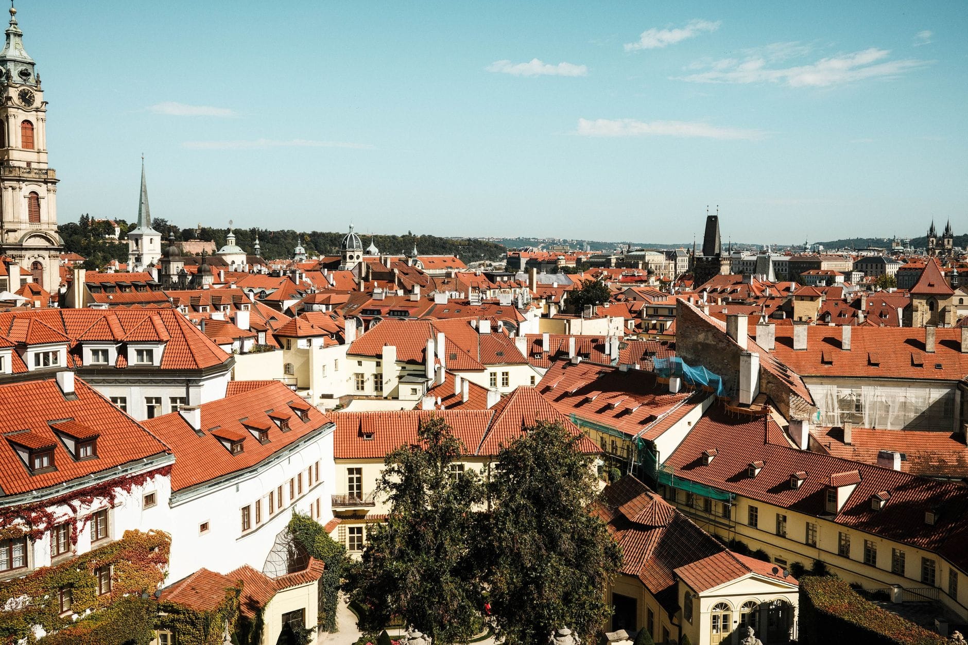 Weekend w europejskim mieście: jak połączyć zwiedzanie z życiem jak lokalny mieszkaniec Czerwone dachy zabytkowej Pragi w słoneczny dzień z błękitnym niebem