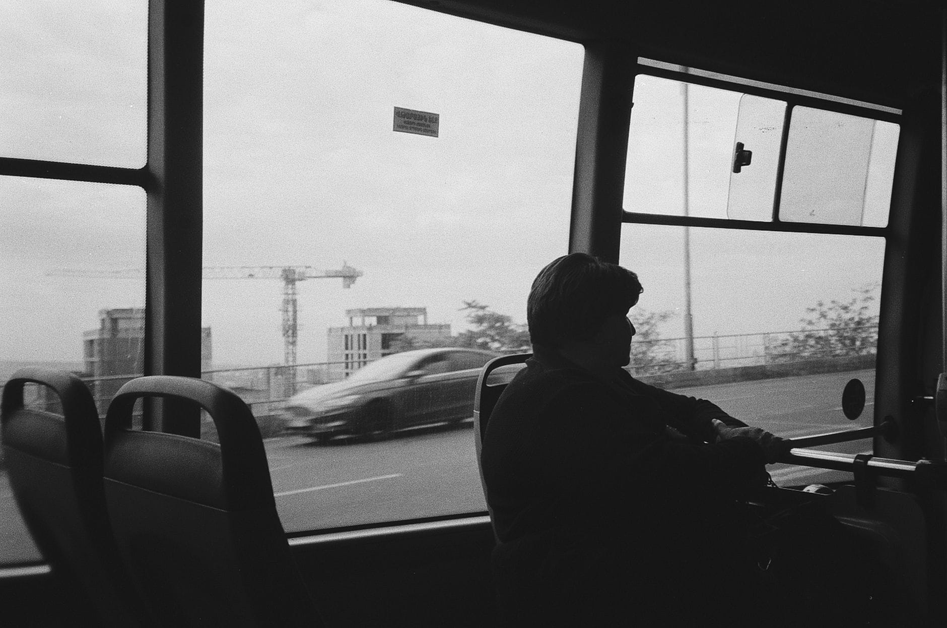 Pasażer w autobusie patrzący na miasto w czarno-białym kadrze
