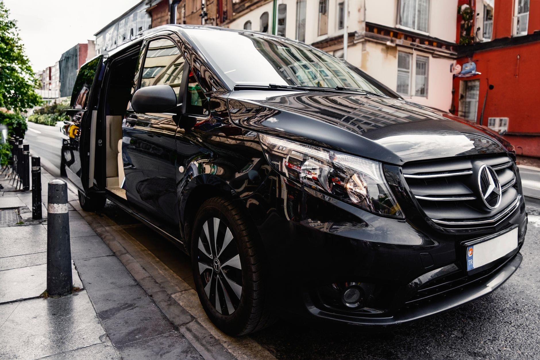 Bus Polska Niemcy: koszt door to door vs przystanek, co wychodzi taniej w praktyce? Czarny bus Mercedes-Benz zaparkowany przy ruchliwej miejskiej ulicy