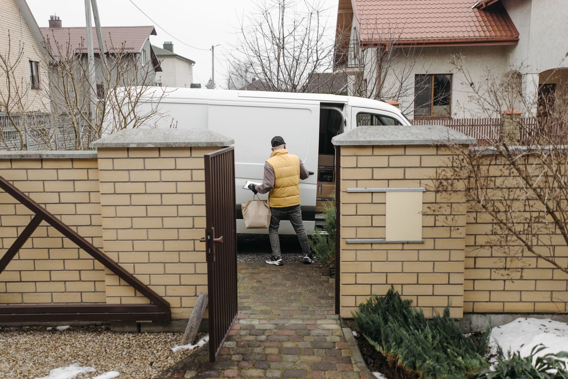Kurier wypakowuje kartony z busa na podwórku między blokami