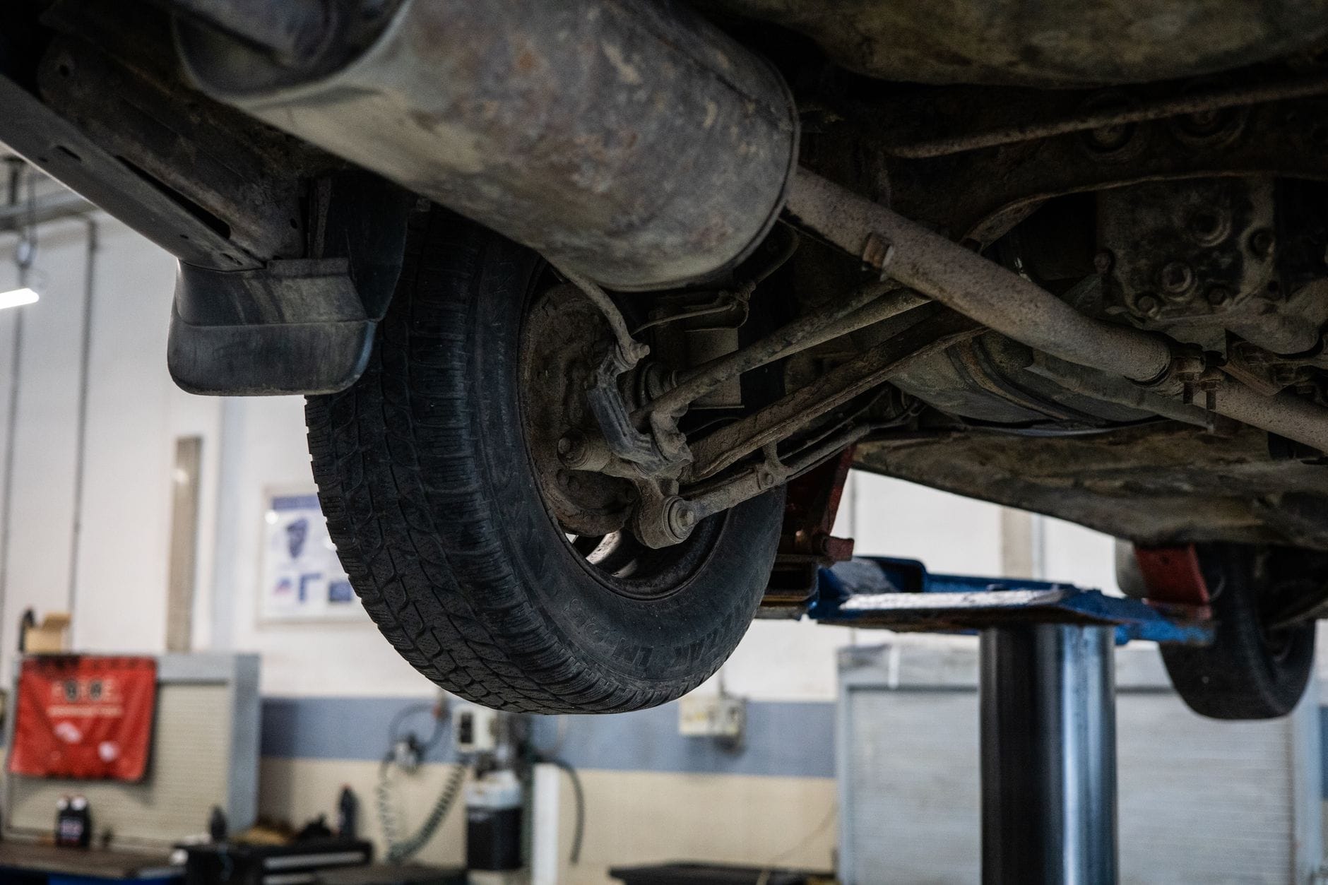 Mechanik ogląda od spodu układ wydechowy samochodu na podnośniku