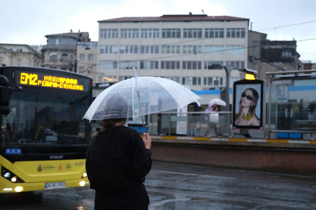 Kobieta z przezroczystą parasolką czeka na przystanku autobusowym w Stambule