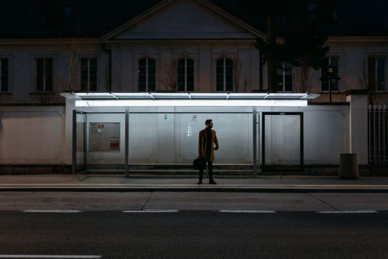 Mężczyzna stojący samotnie nocą na przystanku autobusowym